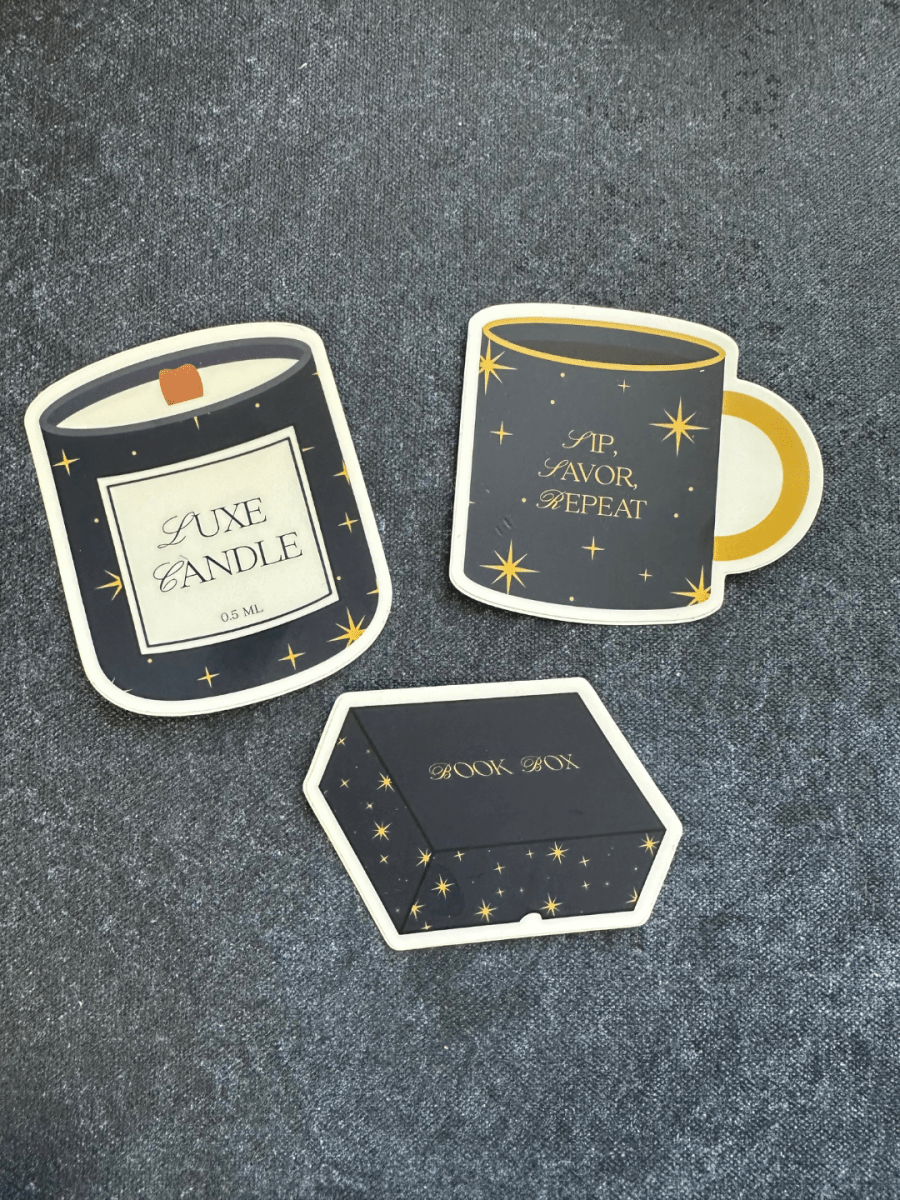 Set of decorative stickers resembling a candle, mug, and box on a textured surface.