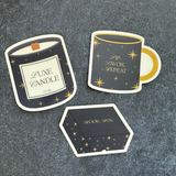 Set of decorative stickers resembling a candle, mug, and box on a textured surface.