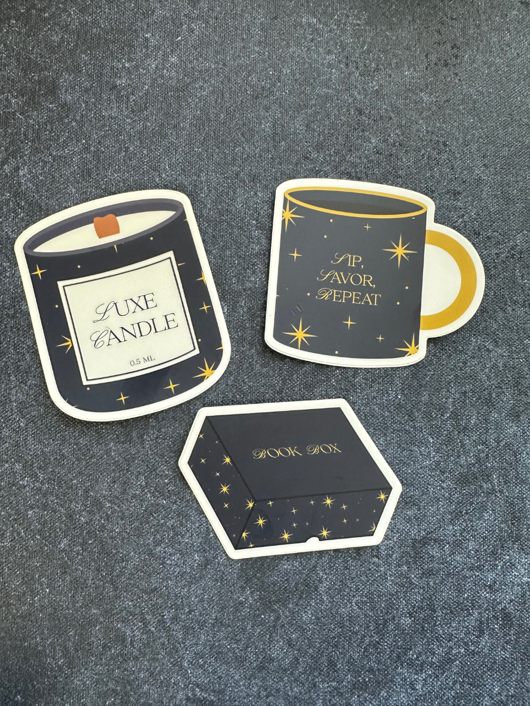 Set of decorative stickers resembling a candle, mug, and box on a textured surface.