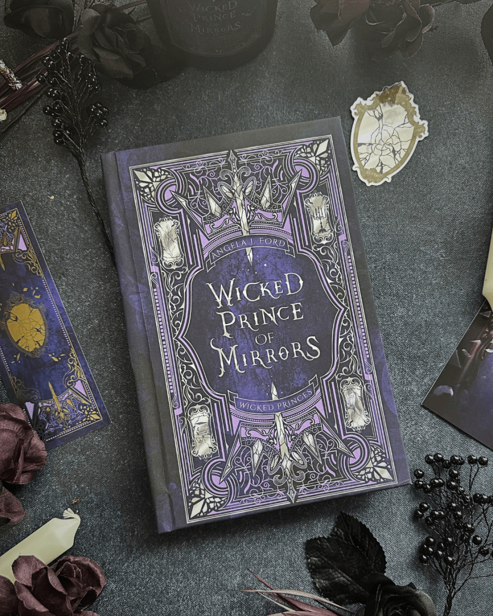 Book titled 'Wicked Prince of Mirrors' on a dark surface with decorative elements.