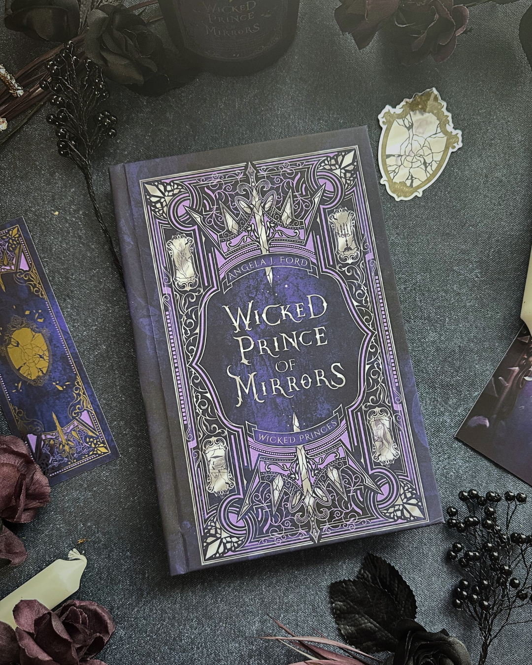 Book titled 'Wicked Prince of Mirrors' on a dark surface with decorative elements.